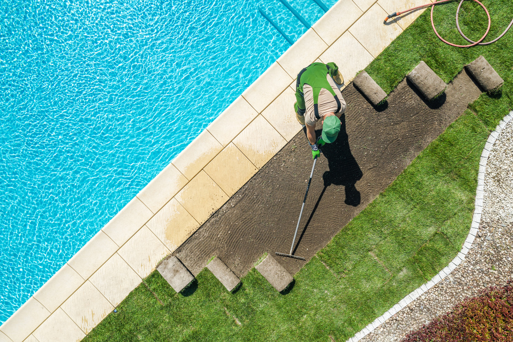 an aerial view of a person landscaping near a swimming pool